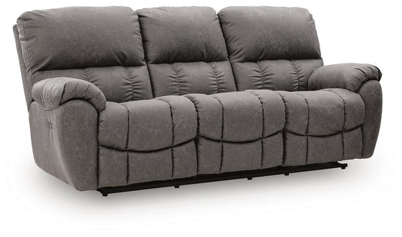 Dark gray reclining sofa with padded arms and adjustable headrests, tufted cushions