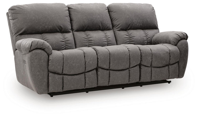Dark gray reclining sofa with padded arms and adjustable headrests, tufted cushions