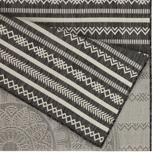 Indoor/outdoor area rug corner detail with navy and beige stripes, zigzags, and small motifs
