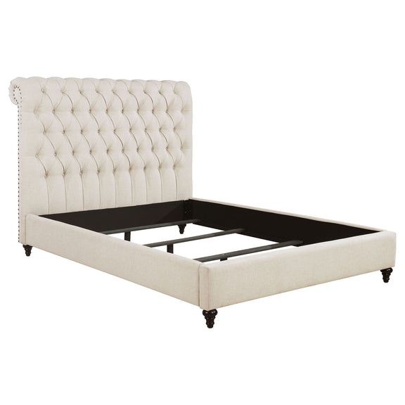 Beige tufted upholstered bed with rolled back headboard and dark feet