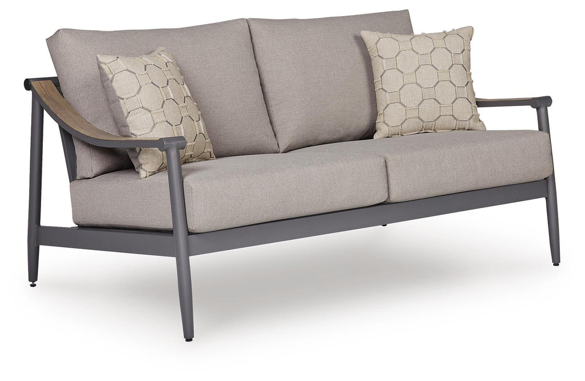 Gray outdoor loveseat with padded arms, sloped back, and two hex-pattern throw pillows.