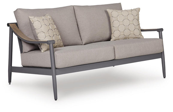 Gray outdoor loveseat with padded arms, sloped back, and two hex-pattern throw pillows.