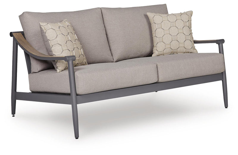 Gray outdoor loveseat with padded arms, sloped back, and two hex-pattern throw pillows.