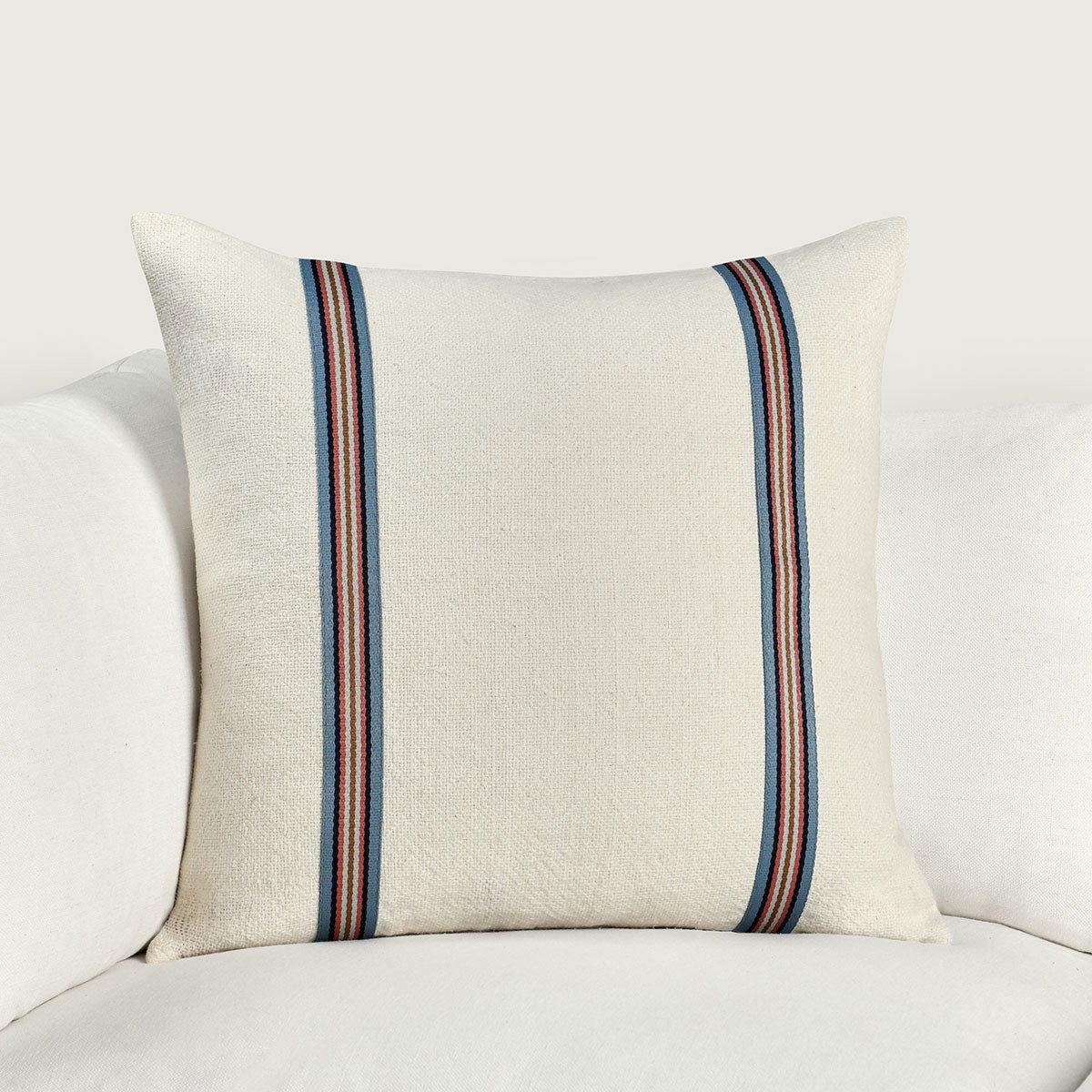 Ivory square pillow with navy, red, and tan stripe band on front