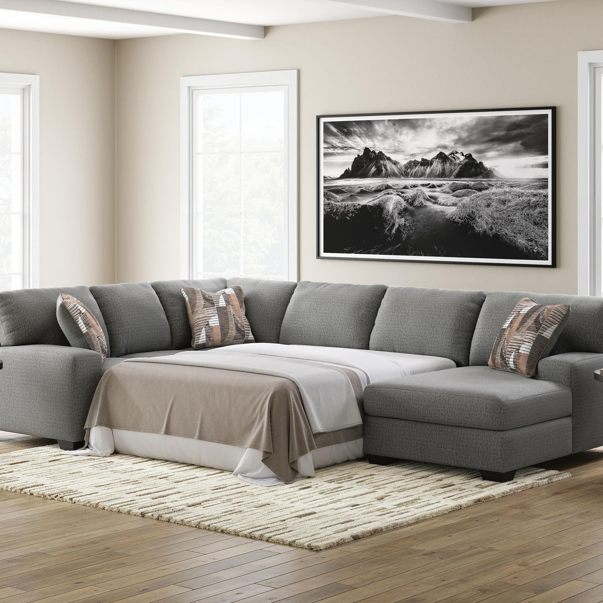 Gray chaise sectional sofa with sleeper cushion and patterned throw pillows