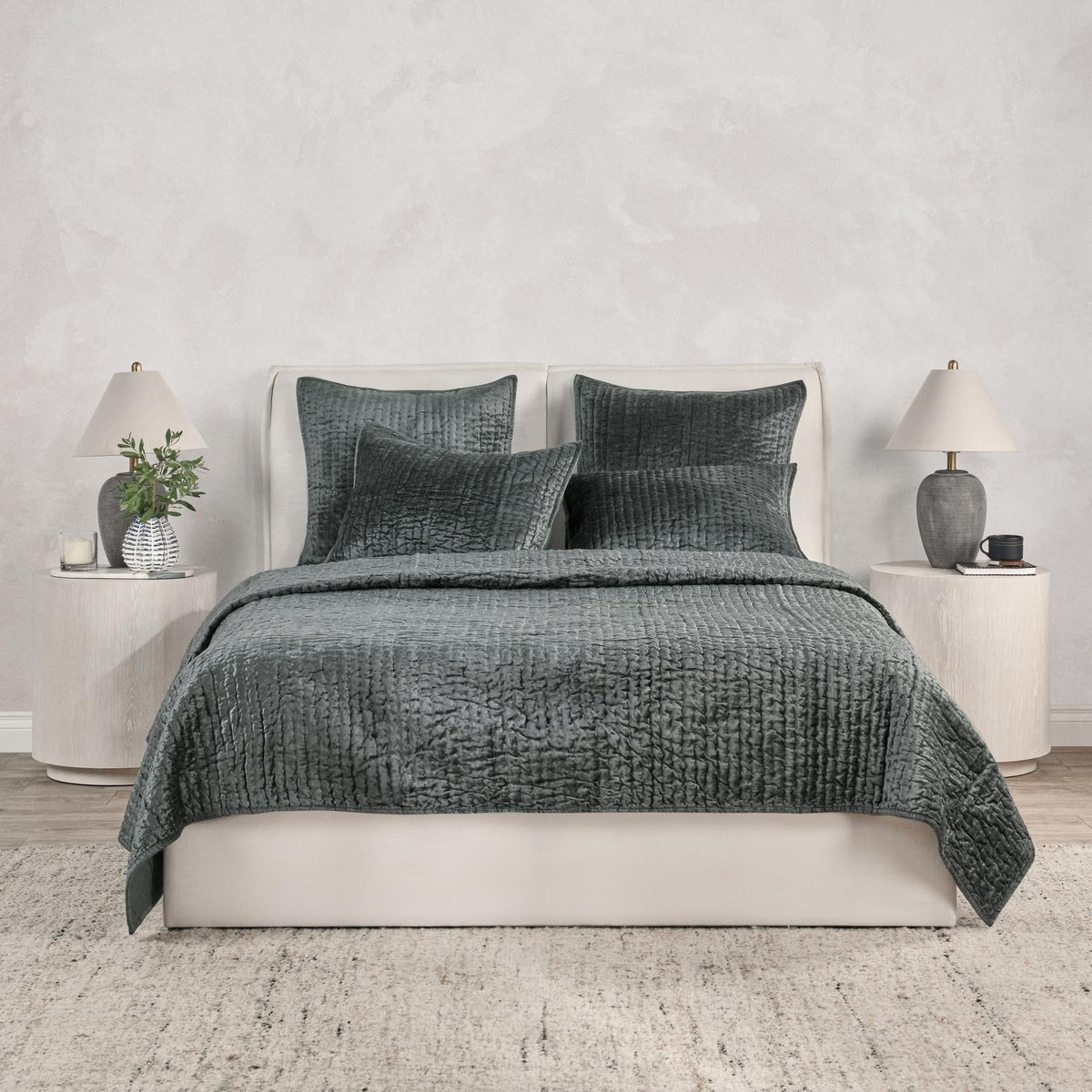Gray velvet quilt with matching pillow set on a white bed