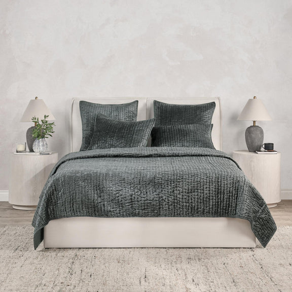 Gray velvet quilt with matching pillow set on a white bed