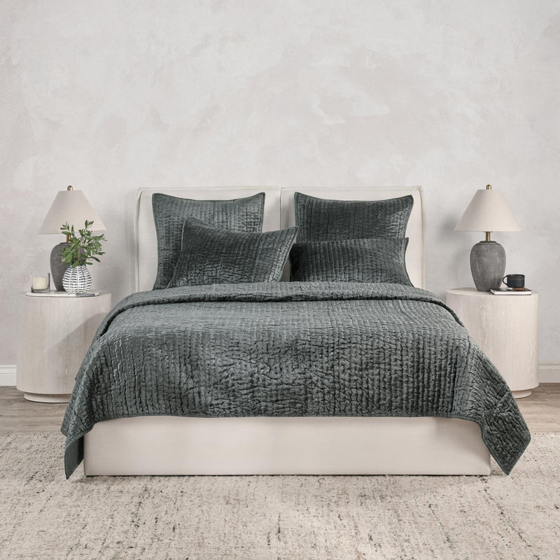 Gray velvet quilt with matching pillow set on a white bed