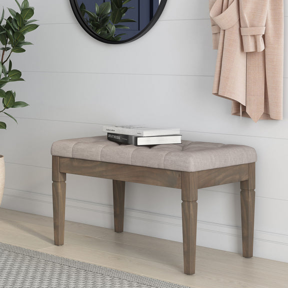 Gray upholstered ottoman bench with dark wooden legs and tufted seat top