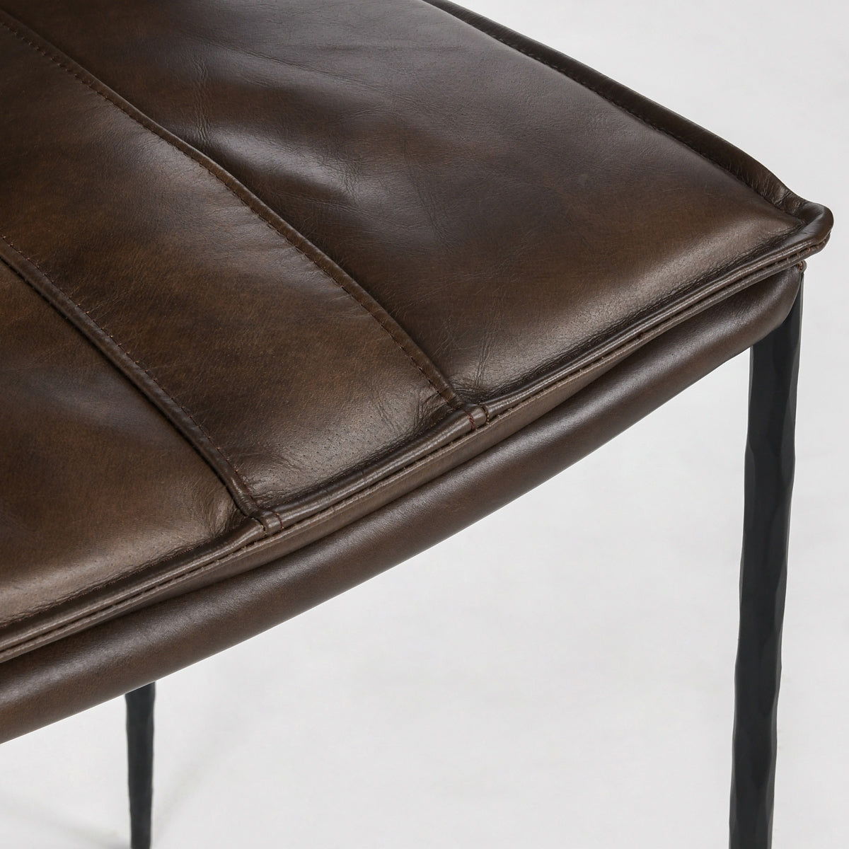 Brown leather bar stool seat cushion with stitched edges and rounded front corner.