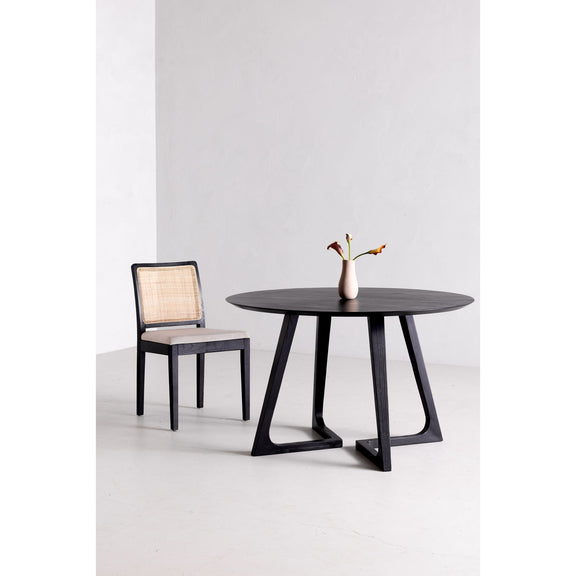 Round dining table with dark tabletop and four-sided pedestal base with X cutouts
