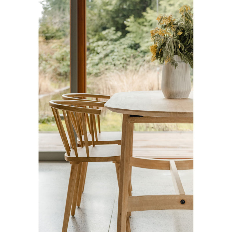 Small dining table in light oak with curved edge top and angled apron supports.