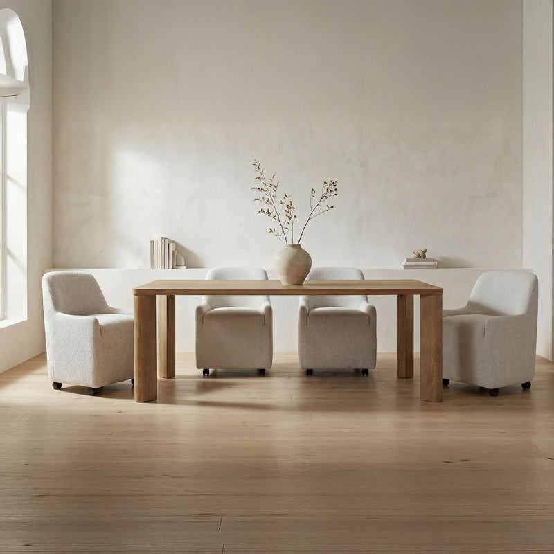 Large wooden dining table with wide legs and upholstered armchairs