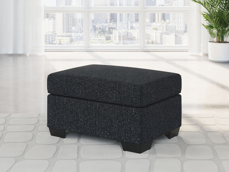 Charcoal upholstered ottoman with black legs and rounded-corner seat cushion
