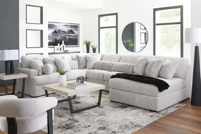 White sectional sofa with chaise, padded ottoman seat, and textured cushion back