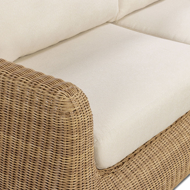 Close-up of outdoor sofa armrest and white cushion with woven wicker texture