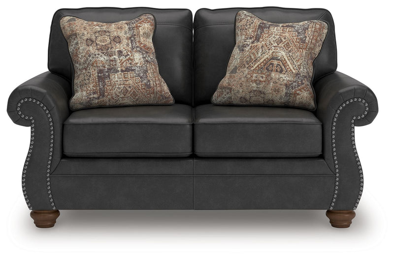 Dark gray sofa with rounded arm details and two patterned accent pillows