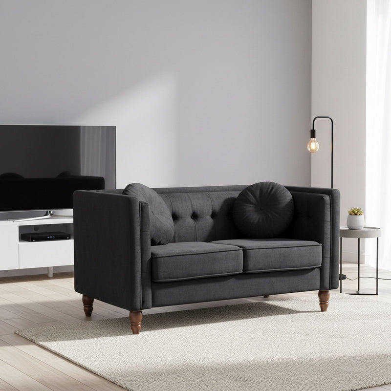 Black fabric two-seater loveseat with tufted back and rounded bolster pillow