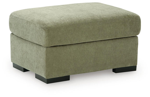 Green fabric ottoman with rounded top, low base, and dark block feet