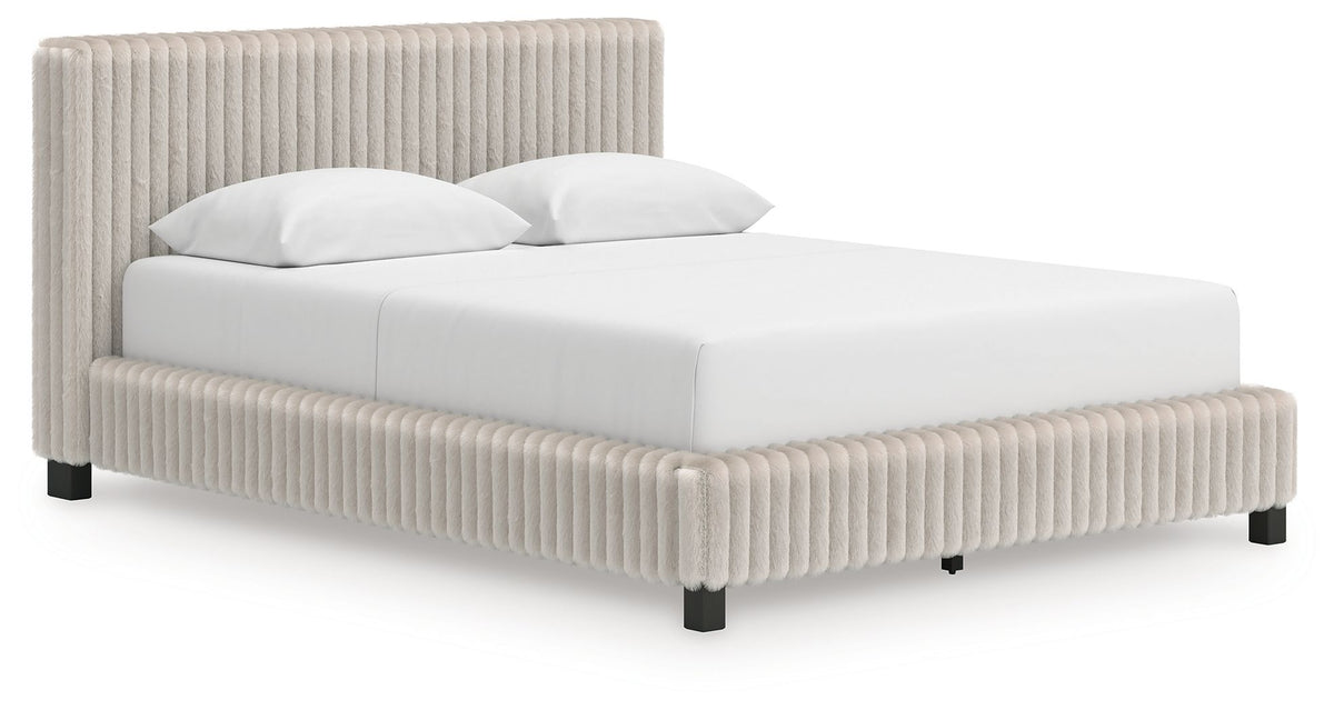 White upholstered bed with tall vertical-ribbed headboard, low platform frame, black legs