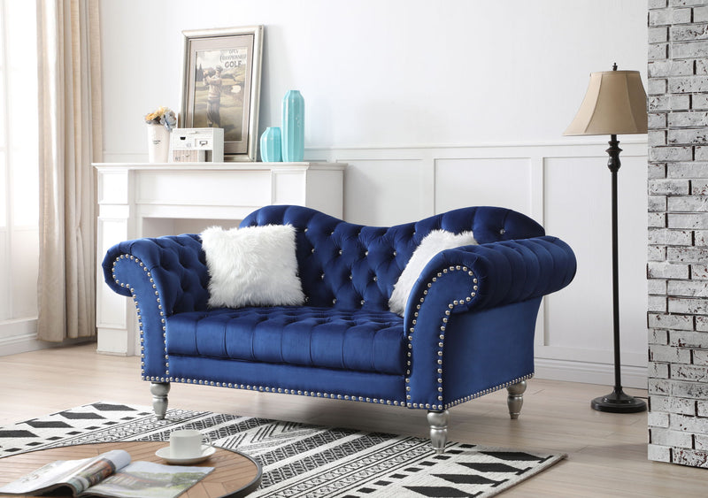 Blue velvet round arm loveseat with tufted back, nailhead trim, and two white faux fur pillows.