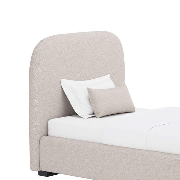 Light gray upholstered bed with tall rounded headboard and side panel, with pillows