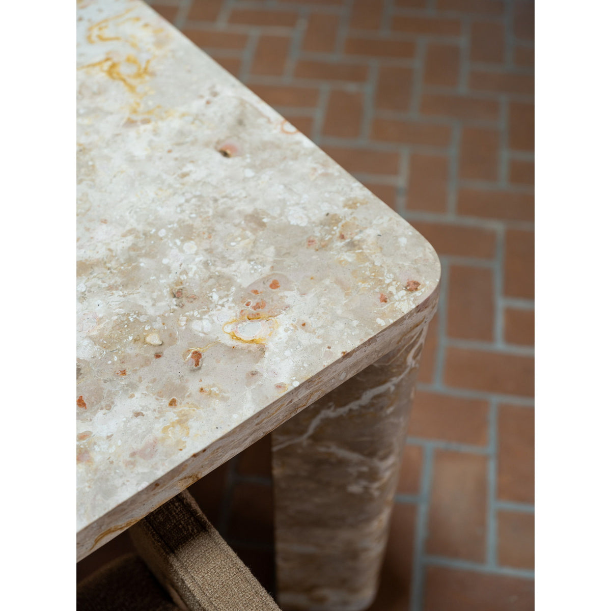 Stone-look dining table corner with mottled beige tabletop and sturdy leg