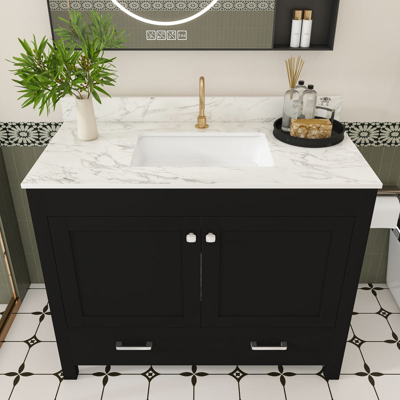 Black bathroom vanity with two doors and two drawers, white countertop, brass single faucet