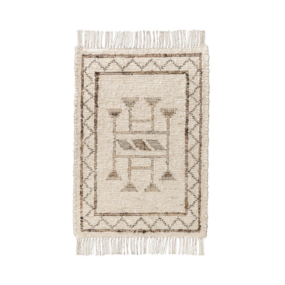 Ivory area rug with dark central geometric design and fringed border edges
