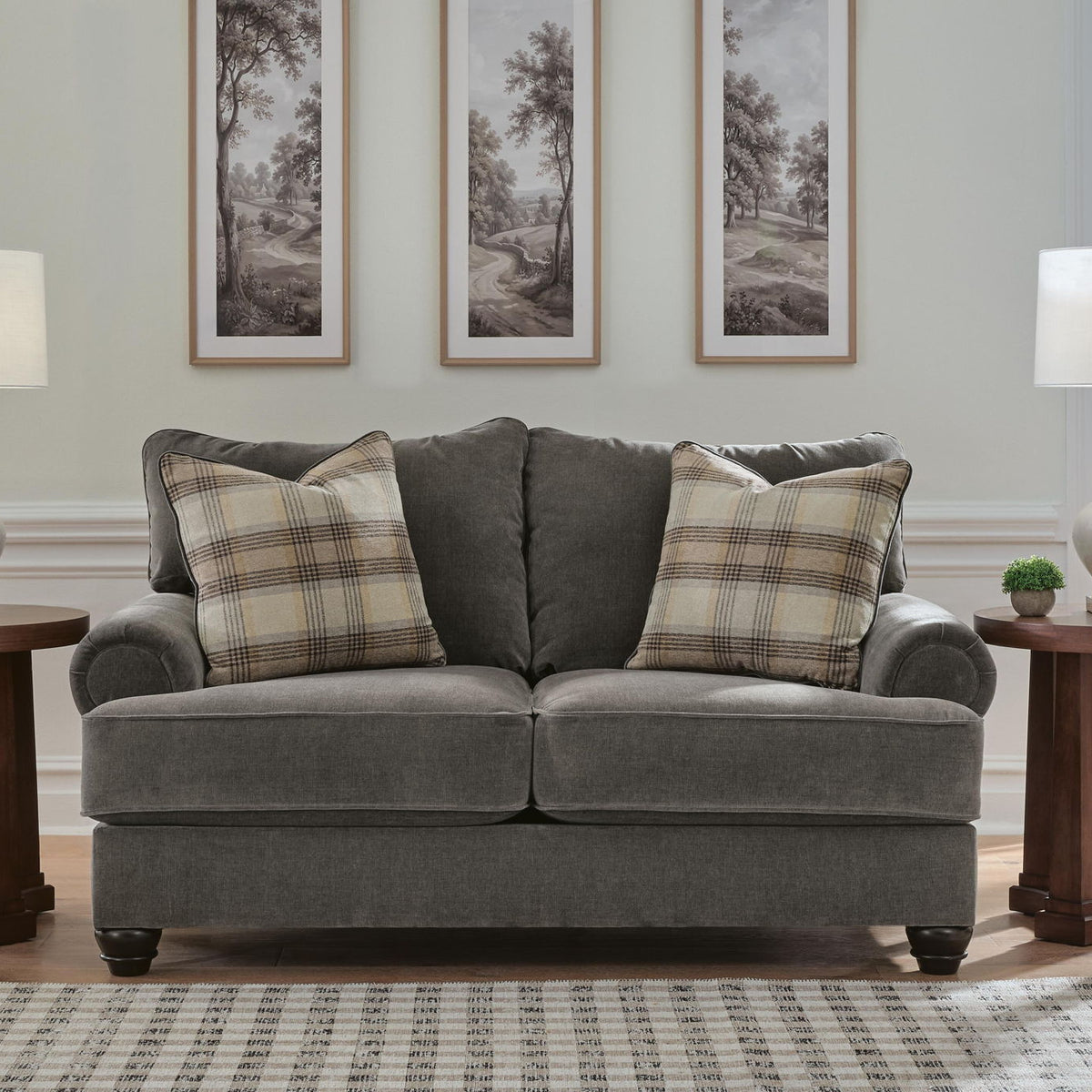 Gray fabric loveseat with rolled arms and plaid throw pillows