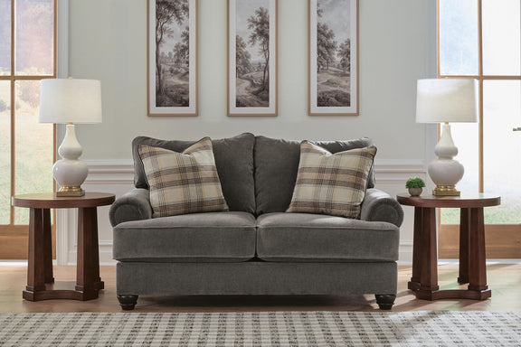 Gray fabric loveseat with rolled arms and plaid throw pillows