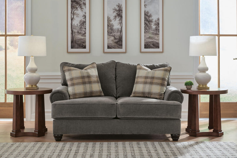 Gray fabric loveseat with rolled arms and plaid throw pillows