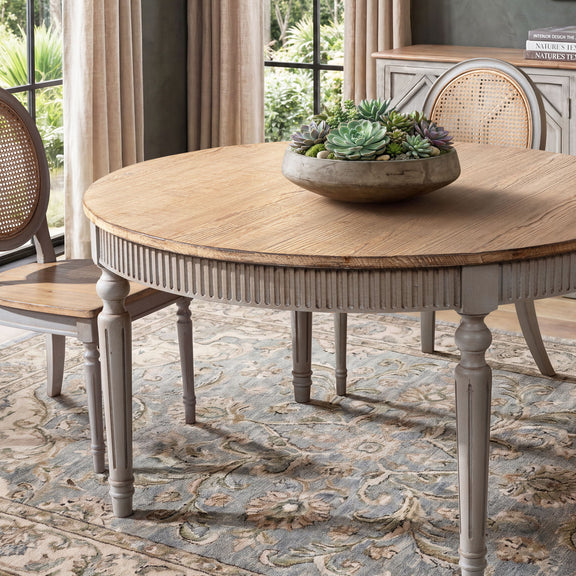 Round dining table with light wood top, ridged apron, and gray turned legs