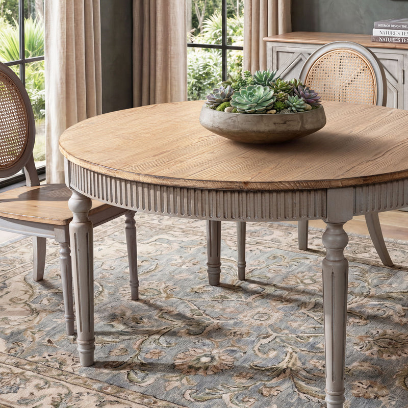 Round dining table with light wood top, ridged apron, and gray turned legs