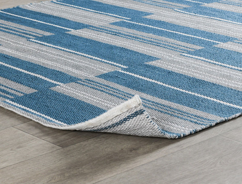 Indoor/outdoor striped rug corner with blue and ivory horizontal lines and bound edge