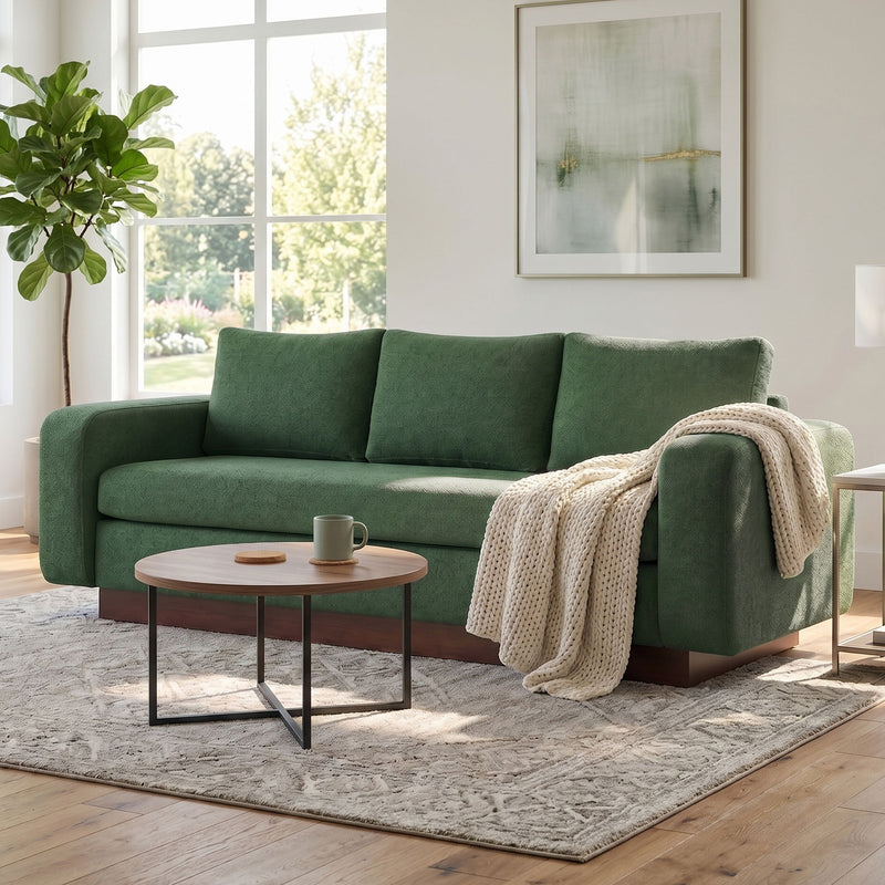 Green 3-seater sofa with three back cushions and beige throw draped over arm