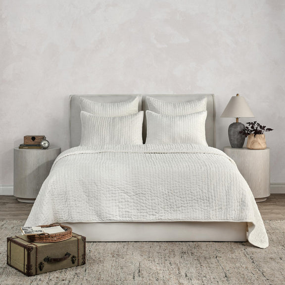 White velvet quilt set with textured duvet and two pillow shams on bed.