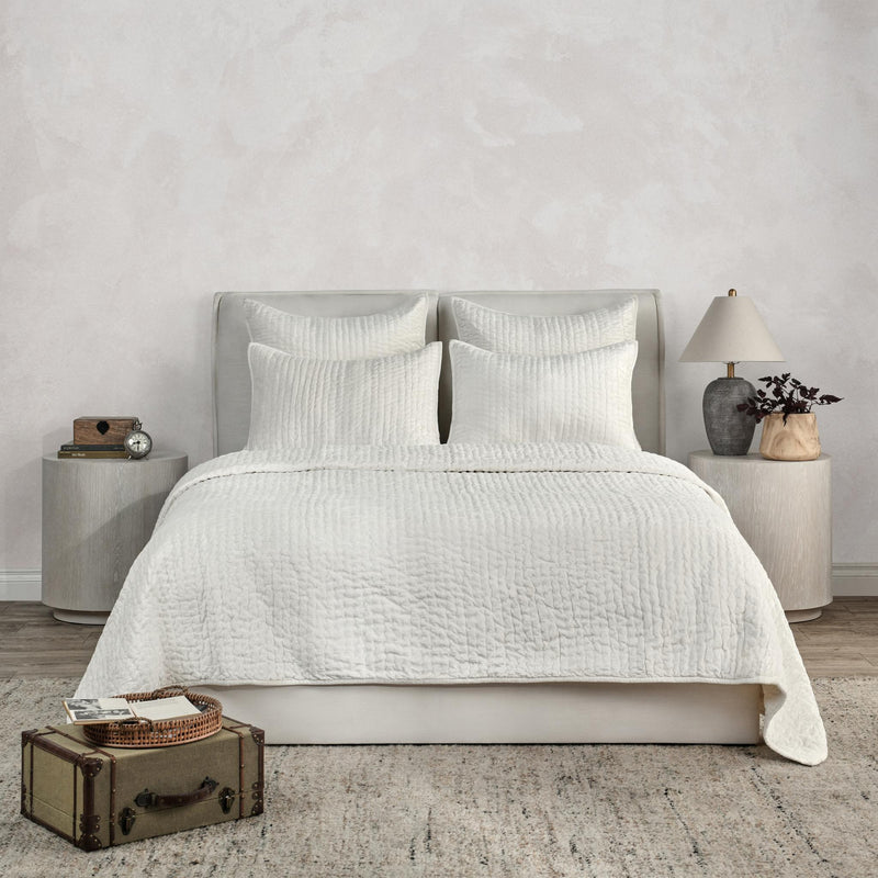 White velvet quilt set with textured duvet and two pillow shams on bed.