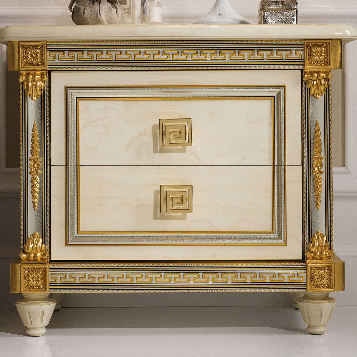 Beige nightstand with white marble-look top, gold-trim drawer and decorative legs.