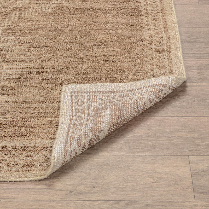 Desert brown hand-knotted rug with detailed border along the folded edge.