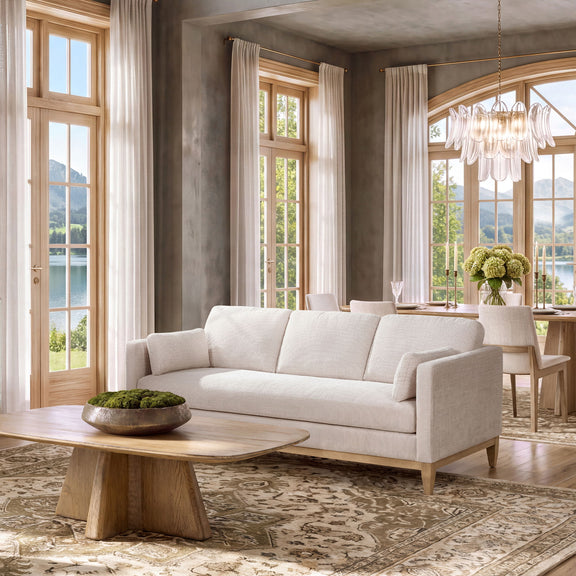 Light beige upholstered sofa with three seat sections, rounded arms, and wooden legs