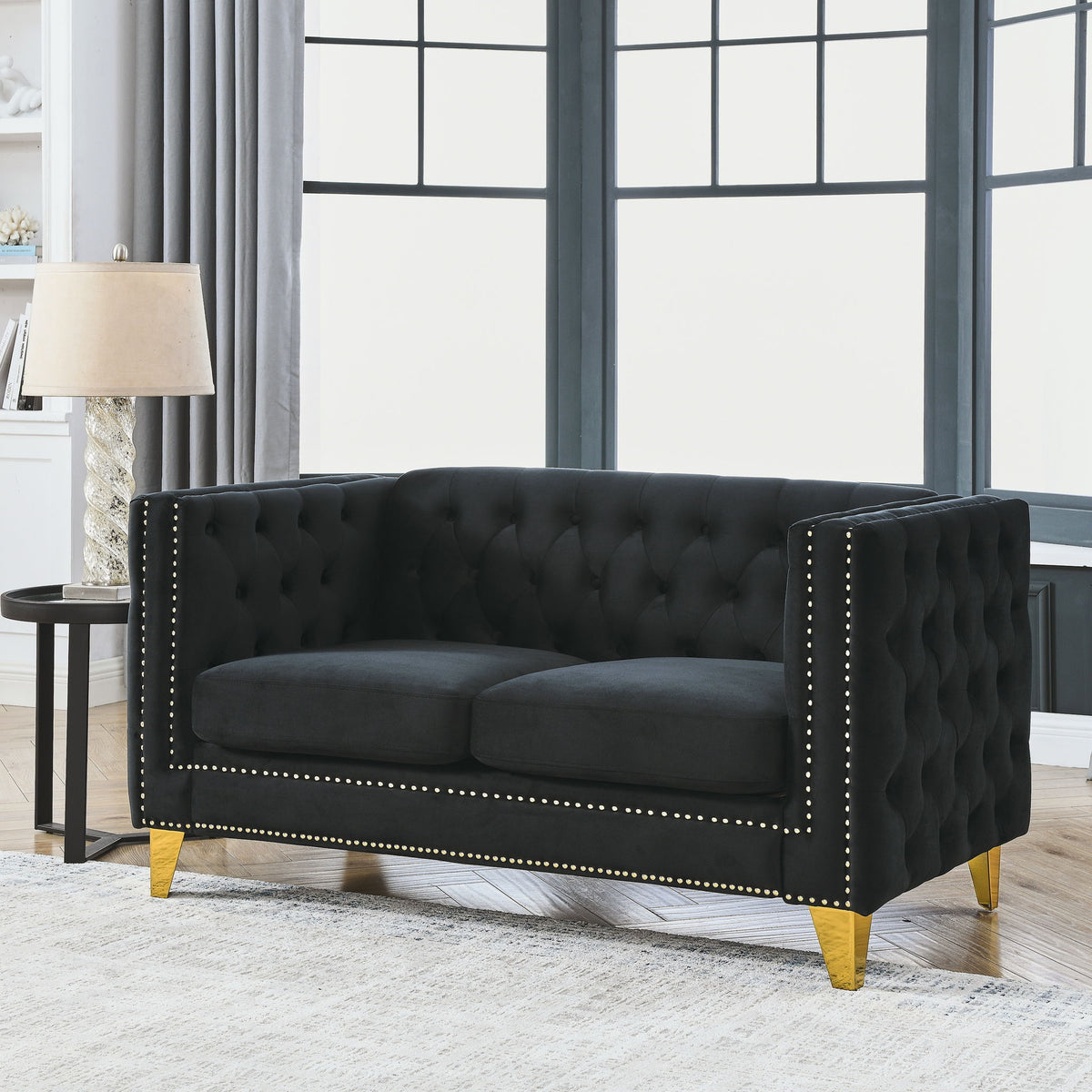 Black button-tufted loveseat with studded trim, padded arms, and gold-toned legs