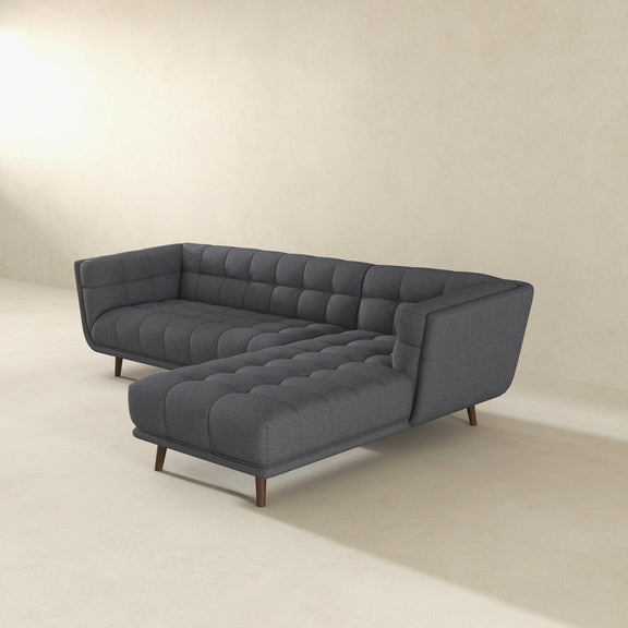Dark gray tufted L-shape sectional sofa with curved seat cushions and tapered legs