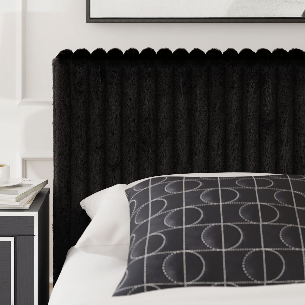 Black upholstered bed with ribbed headboard, white pillow, and patterned throw cushion.