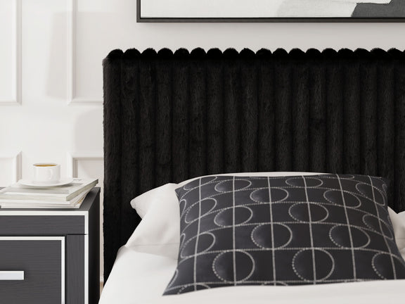 Black upholstered bed with ribbed headboard, white pillow, and patterned throw cushion.