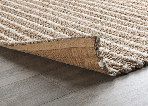 Natural fiber rug corner detail in light beige with bound edge and fringe