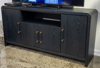 Large black TV stand with open center shelf and two cabinet doors with gold knobs