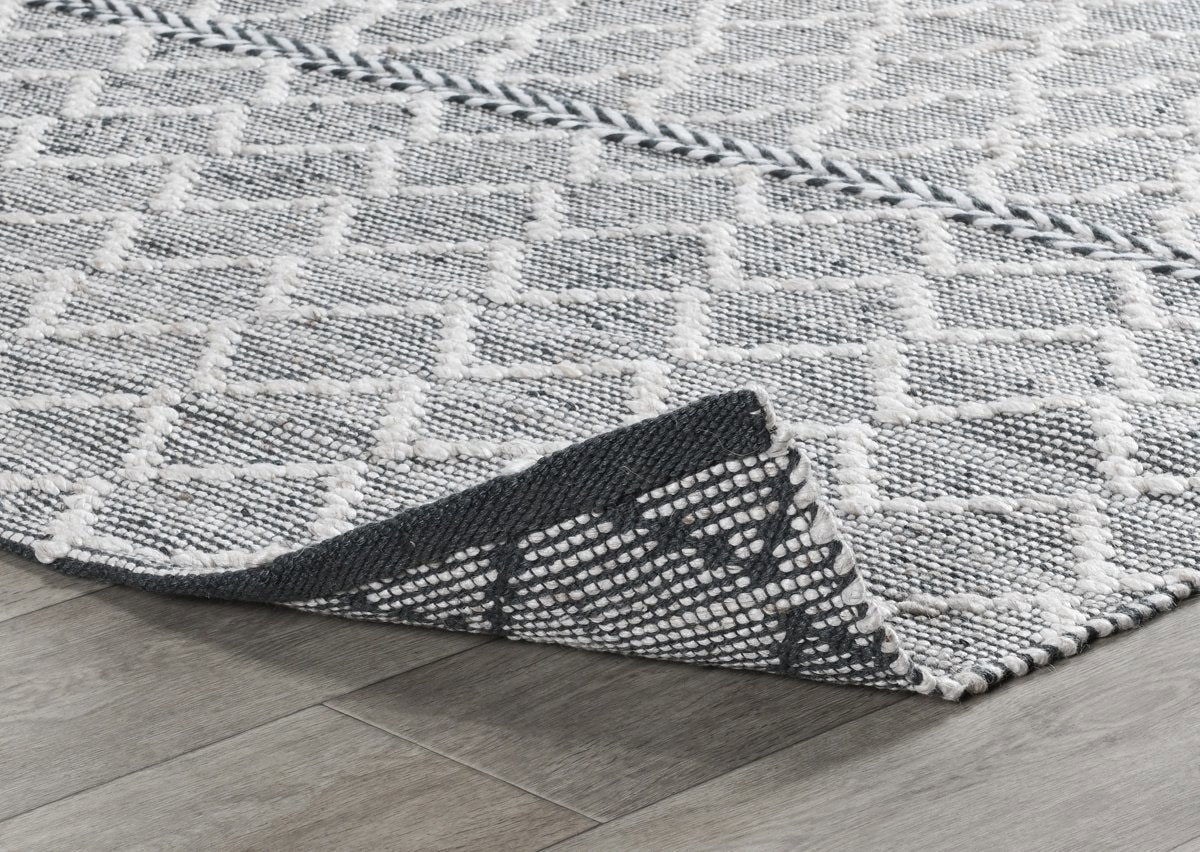 Gray indoor/outdoor rug corner with black binding and white geometric weave