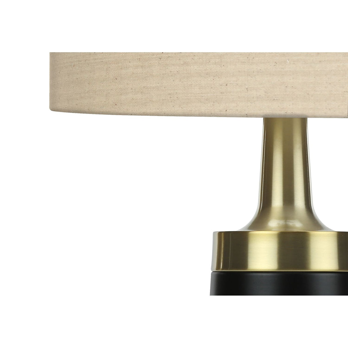 Close-up of resin table lamp: cream fabric shade and brushed gold neck over black base