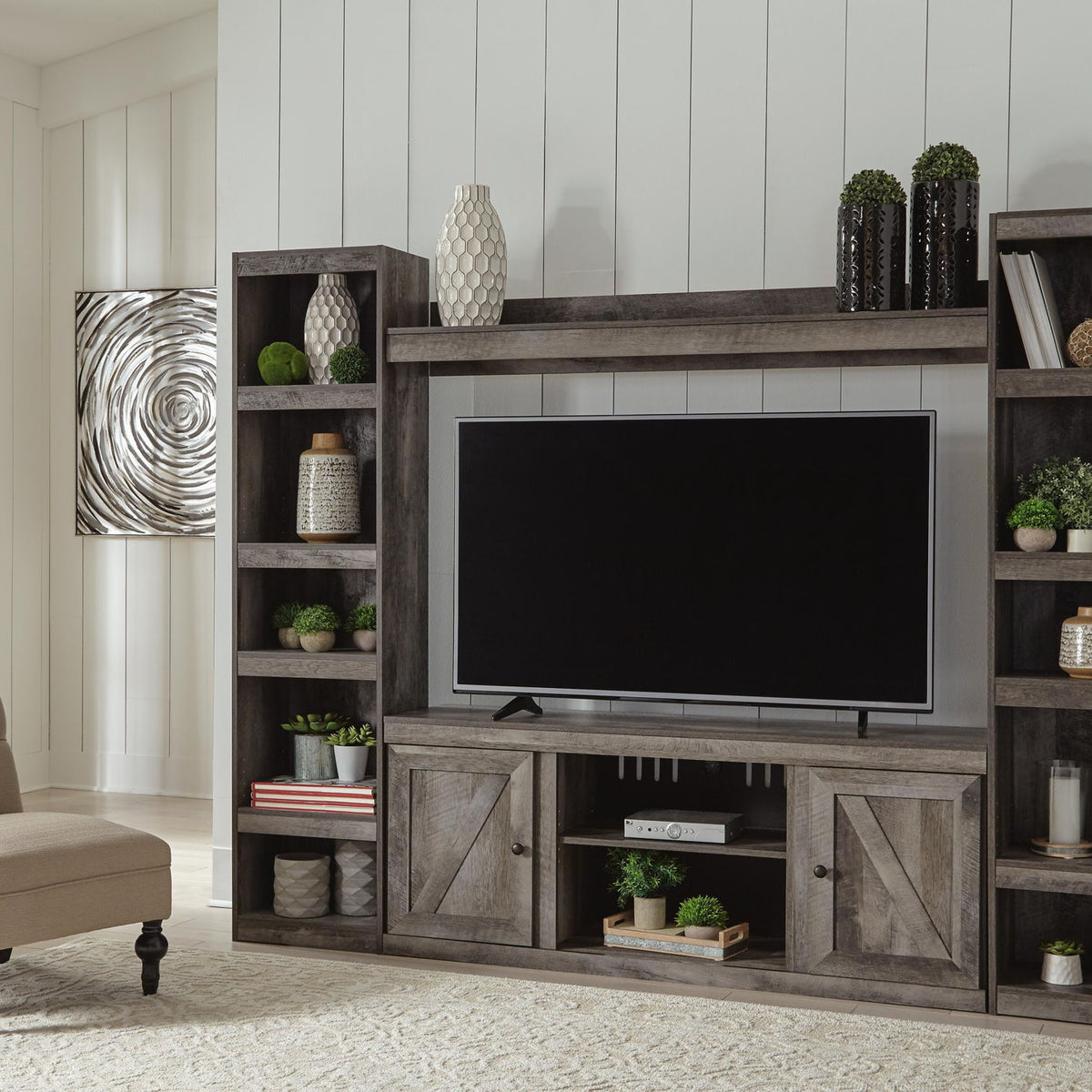 Gray entertainment center with TV, shelving, and central fireplace-style opening